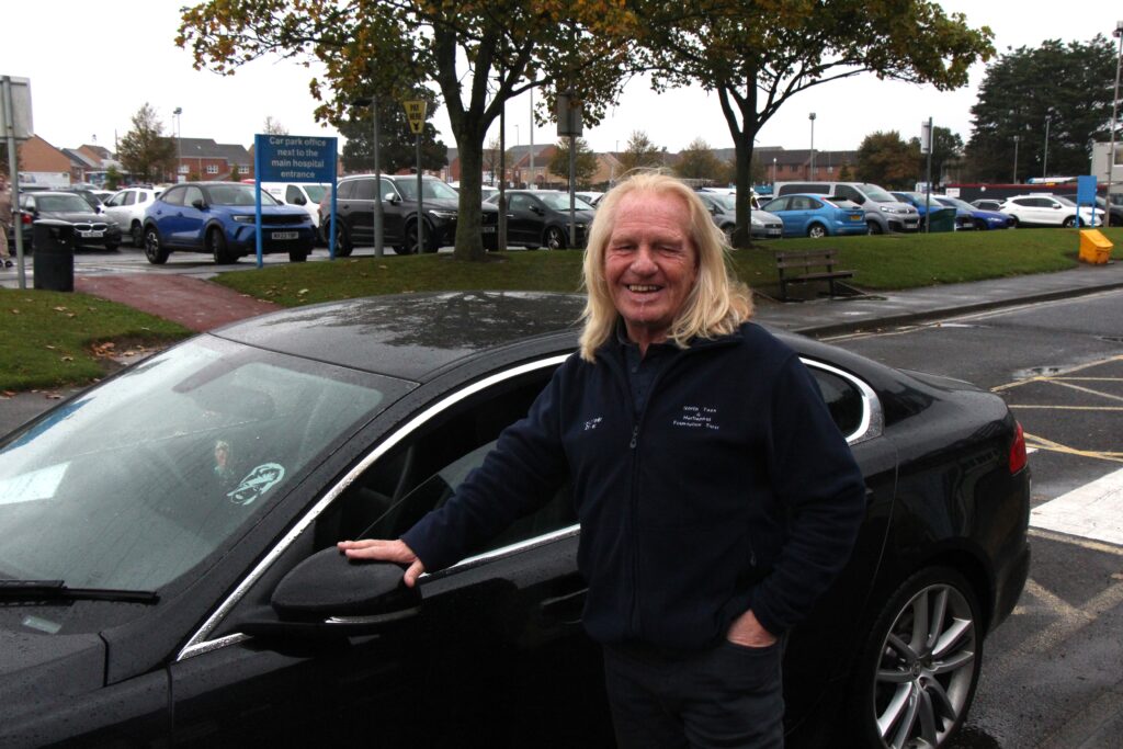 Robbie Earl stands in front of a car.