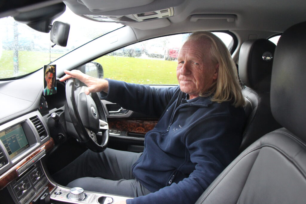 Robbie Earl sits behind the wheel in a car.