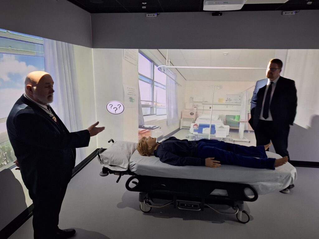 Visitors stood in an immersive room with a simulated ward on the wall.