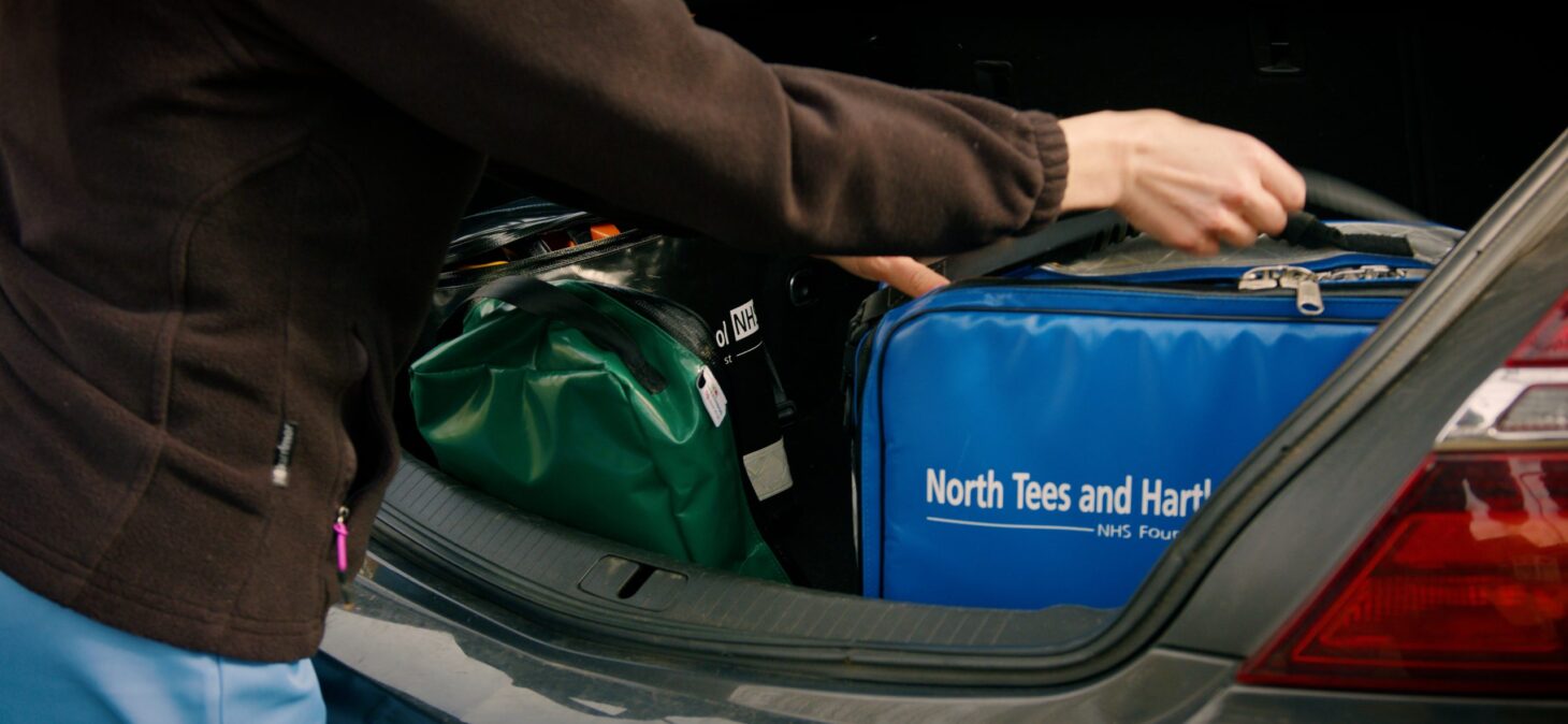 Hand of community nurse grabbing kitbag from car