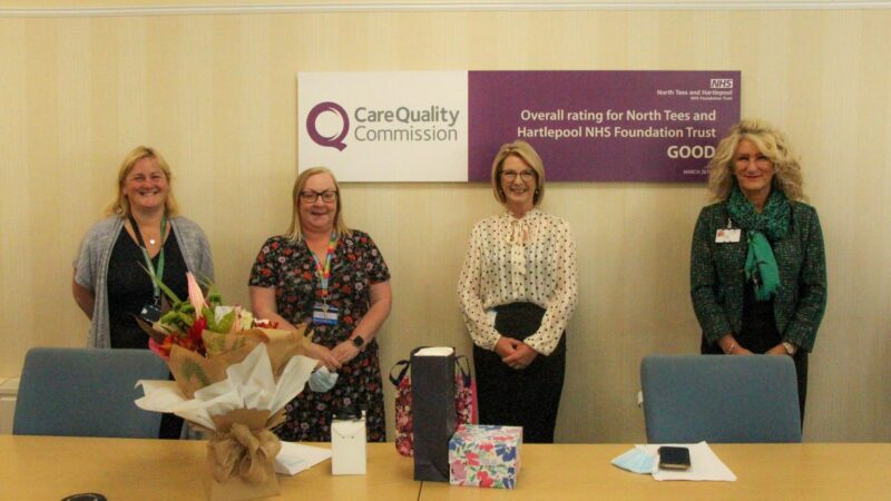 Lynne Taylor stands with colleagues, including chief executive Julie Gillon. On the table in front of her are flowers and gifts.