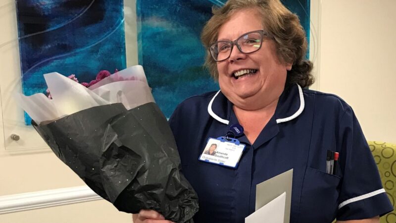 Amanda Southcott holds a bouquet of flowers and two cards.